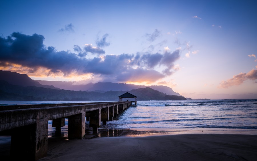 Golden Hour Serenade: Beachside Pier Over Mountain Horizon