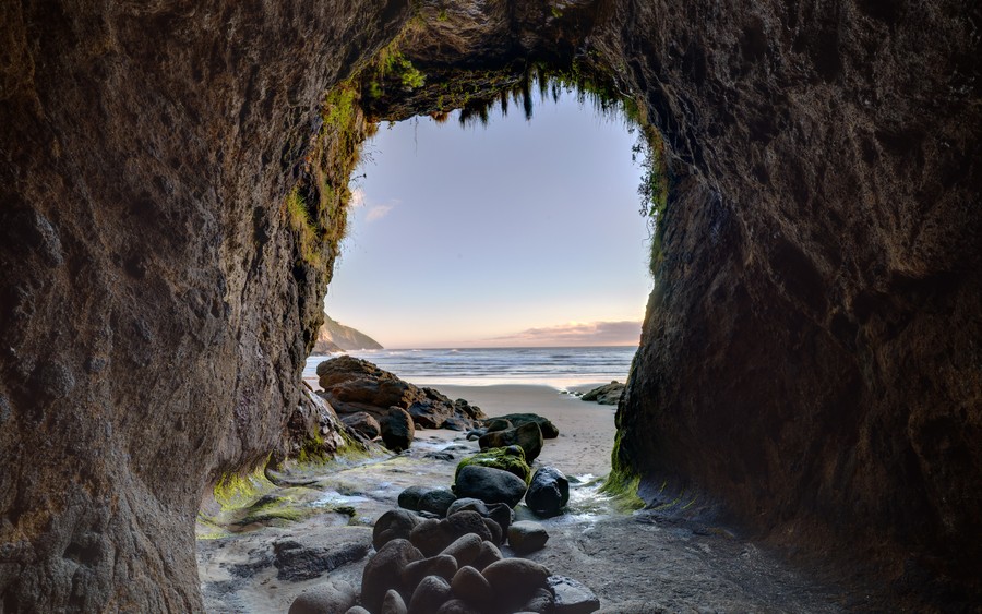 Cave to Coast: Serene Ocean Sunset Through Natural Rock Arch | Tranquil Nature Wallpaper