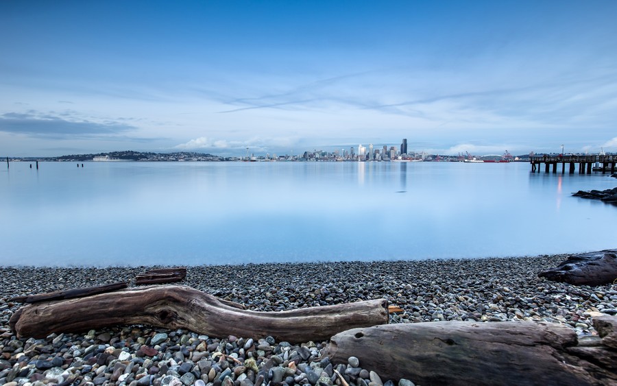 Coastal Serenity: Reflective Waters and City Skyline at Dusk