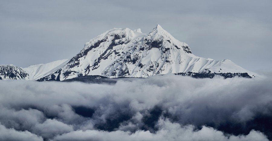 Majestic Snow-Capped Alpine Peak Piercing Through Cloud Layers