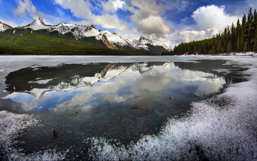 Tranquil Reflections: Frozen Lake Mirroring Snow-Capped Mountains