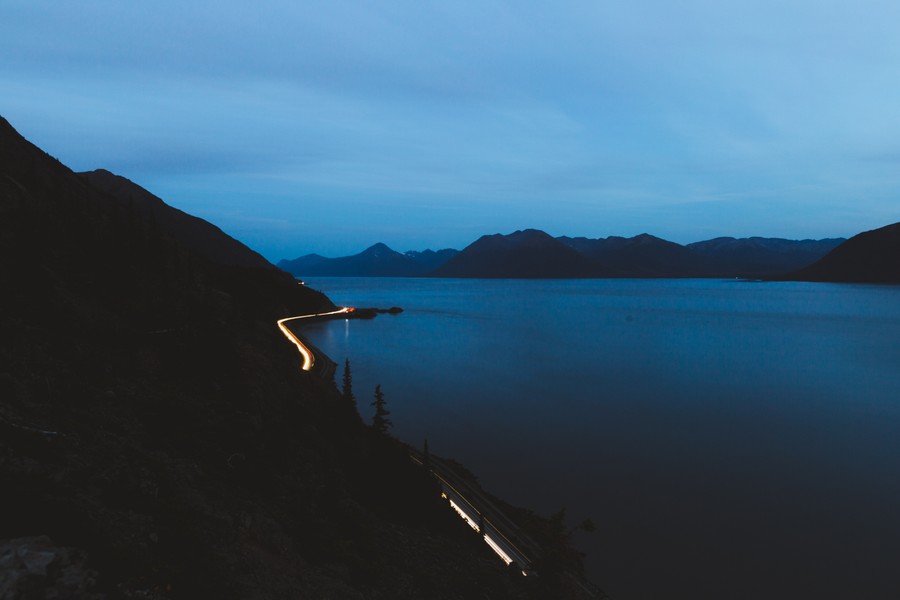 Twilight Serenity: A Winding Road by Calm Waters and Majestic Peaks