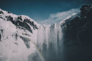 Frozen Majesty: Icy Cliffs & Ethereal Rainbow Waterfall - Niedliches Hintergrundbild